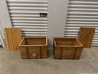Photo showing both wooden crates with matching detached lids placed beside them on concrete floor.