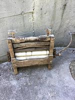 Photo showing front side of antique wooden clothes wringer with white rollers and hand crank