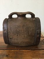 Front view of the antique wooden jug showing the rectangular body, integrated handle, and metal bands on the sides.