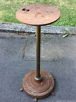 Rustic cast iron stand showing full height and round top plate with rust and wear.