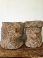 Front view of two natural seagrass baskets, one larger and one smaller with lid folded at top