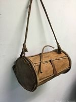 Front-side view of vintage wooden drum with straps and inscription visible on side.