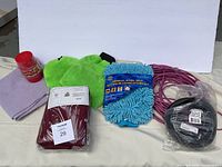 Full lot items including linens, cleaning mitts, electrical cords, red container, and game