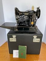 Exterior view of sewing machine on top of carrying case with instruction manual and lot tag