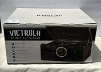 Box front showing brand Victrola, product image of 6-in-1 turntable with wooden casing and analog tuning dial