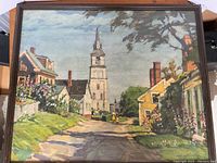 Framed vintage print showing woman and child walking down village street with church steeple in background, bright colors and good condition.