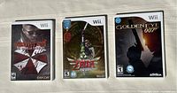 Photo showing three Wii game cases: Resident Evil Umbrella Chronicles, Zelda Skyward Sword, and 007 GoldenEye side by side.