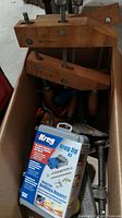 Wide shot showing multiple wood clamps inside a box with the sealed Kreg Jig R3 kit case resting on top.