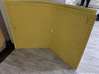 Two large yellow cutting mats leaning against wall showing overall condition and size