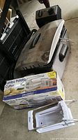 Oster deep fryer with lid, basket inside, and two potato cutters, one boxed