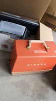 Orange vintage Singer portable sewing machine case with handle and clasps