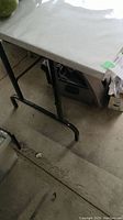 Top view showing white laminated rectangular tabletop with smooth edges and black metal leg visible underneath.