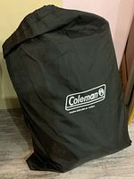 Black Coleman storage bag labeled 'Twin-Double High' containing mattress.