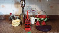 Kitchenware including milkshake maker, slicer, dishes, salt and pepper shakers and glasses on countertop.