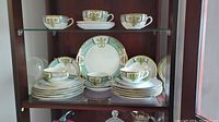 Wide view of Noritake china set showing cups, saucers, bowls, plates stacked in display cabinet