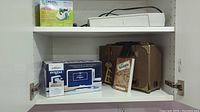 Shelf with Spellbinders Prism box, Artograph Light tracer, brown case, and Xyron adhesive box