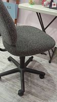 Side view of grey fabric office chair on caster wheels.
