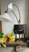 Full view of the floor lamp displaying the lamp with conical shade, yarn feeder base, and flexible necks.