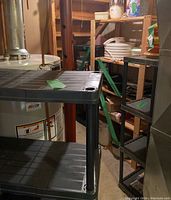 Photo of one black plastic shelving unit near water heater in basement.