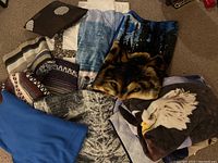 View showing multiple blankets and quilts arranged on carpet including wolf face and eagle head animal-themed blankets, striped blankets, and other patterned quilts.