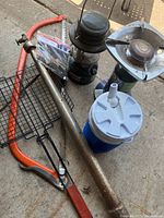 Photo showing the metal band saw, fire pit grill, camping lantern, propane stove, and thermos.