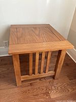Side view of one solid wood mission style end table showing slatted side design and wood grain on top.