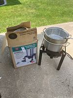 Photo showing complete set box beside assembled fry and boil set outside on concrete. Box depicts product details and model number.