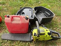 Poulan gas powered chainsaw with black protective blade cover, red empty gas can and black carrying case all placed on grass.