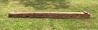 Full length side view of salvaged barn beam showing length and surface texture.