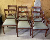 Set of six wood dining chairs with green upholstered seats, four standard and two captain chairs visible
