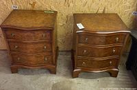 Pair of two brown wooden 3-drawer end tables or nightstands with curved drawer fronts and metal ring pull handles on a concrete floor against a plywood wall.