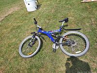 Full view of blue Trek 750 mountain bike laying on grass, shows overall condition and components.