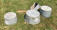 Three round tubs and a triangular planter arranged on grass
