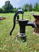 Full front view of entire cast iron hand pump on grass