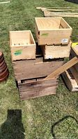 Top view showing a stack of various wooden boxes, some with light unfinished wood and some aged, weathered boxes underneath with branding.