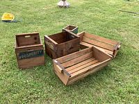 Five wooden crates arranged on grass, showing different sizes and styles including crates with vintage labels and wood slat construction.