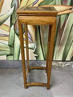 Side view of vintage Chinese hardwood pedestal table showing slender legs and rectangular stretcher base.