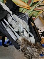 Photo showing the kit contents including multiple duster heads, extension handles, and cleaning accessories stored in a black carrying bag.