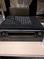 Front view of the black Denon AVR-2807 surround receiver showing vents, power cord, and front panel controls.