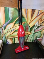 Full upright view of red Dirt Devil vacuum cleaner showing entire body and handle