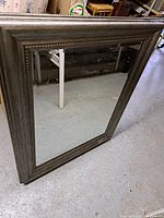 Full frontal view of the large mirror showing beveled edge and wood grain frame.