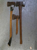 Photo showing all three axes laid out side by side on concrete floor with visible rust and wear.