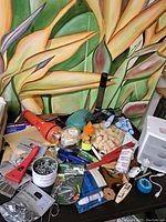 Overview photo showing multiple office supplies and related items including corks, flashlights, clamps, markers, tape, and other small tools.