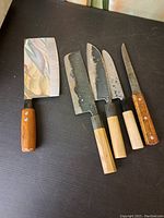 Five knives laid out on black surface