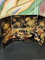 Full view of four-panel Oriental table screen featuring painted rural village scene with houses, trees, and people.