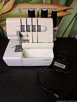 Front and side view of Singer Ultralock sewing machine showing the machine with three black thread spools attached and foot pedal.