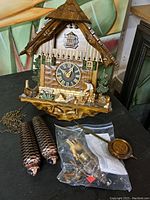 Front view of entire cuckoo clock with weights and pendulum in bag