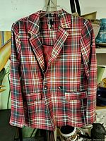 Front view of the red plaid jacket on hanger showing pattern, buttons, flap pockets, and lapels.
