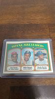 Photo of a 1971 Topps baseball card featuring Joe Torre, Willie Stargell, and Hank Aaron as National League RBI leaders with player portraits and team names