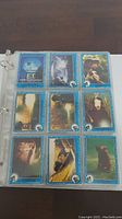 Nine E.T. trading cards arranged in a 3x3 grid inside a binder page, showing various scenes from the film with blue borders and the E.T. logo.